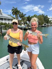 Two anglers proudly displaying their Snook catch while enjoying a sunny day on the water.
