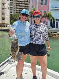 Two anglers proudly displaying a Flounder while enjoying a sunny day on the water.