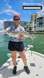 Angler proudly displaying a large Speckled Trout while enjoying a sunny day on the water.