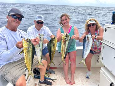A group of four anglers proudly displaying their catch of Mahi Mahi while fishing offshore.