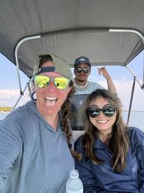 Three friends enjoying a fun moment on a boat, showcasing a relaxed atmosphere while out on the water.