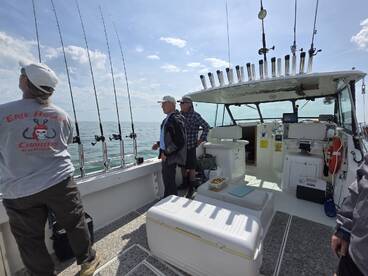 Interior view of a fishing charter boat with anglers preparing for a day on the water, featuring multiple fishing rods and a spacious cabin.