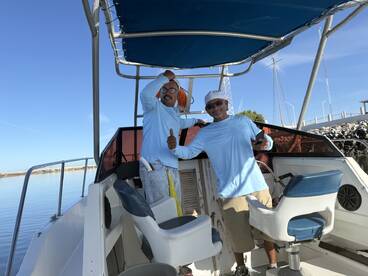 Two crew members inside the boat, showcasing the helm and seating area, ready for a fishing adventure.