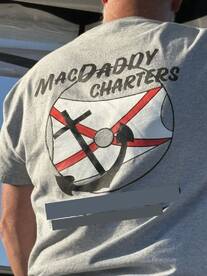 A person wearing a 'MacDaddy Charters' shirt is seen from behind, possibly on a boat, but no fishing activity or catch is visible.