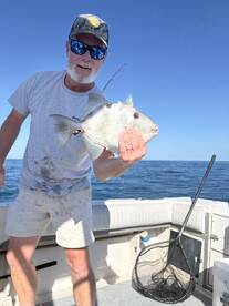Angler proudly displaying a caught fish while fishing on a boat in open waters.