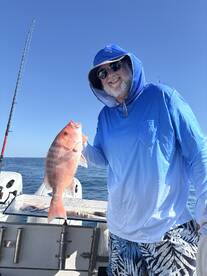 Angler proudly displaying a large Snapper while fishing on a sunny day at sea.