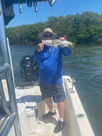 Angler proudly displaying a Snook caught while fishing in a mangrove area, showcasing a sunny day on the water.