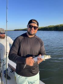 Angler proudly displaying a caught fish while fishing in a scenic waterway, showcasing a beautiful day on the water.
