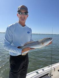 Angler proudly displaying a Redfish while fishing on a sunny day, showcasing the excitement of a successful catch.