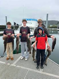 A family proudly displaying their catch of large rockfish at the marina after a successful fishing trip.
