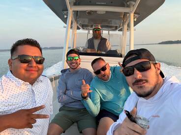 Group of friends enjoying a boat ride, capturing a fun moment on the water with smiles and sunglasses.