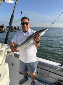 Angler proudly displaying a caught shark while fishing on a boat, showcasing a successful day on the water.