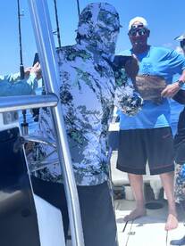 A group of anglers celebrating a successful catch aboard a fishing boat, with one person proudly displaying a large fish.