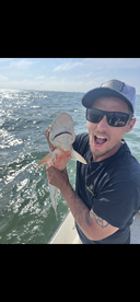 Angler excitedly holding a large Redfish while fishing on a sunny day, showcasing the thrill of saltwater fishing.
