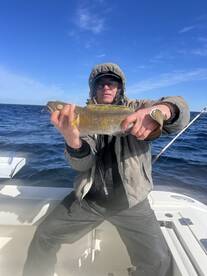 Angler proudly displaying a large fish while fishing on a boat in open waters.