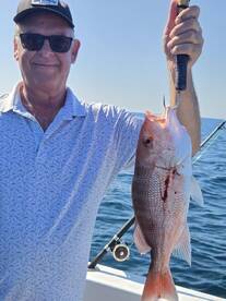An angler proudly displaying a freshly caught Red Snapper while fishing offshore.
