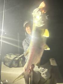 Angler proudly displaying a large bass while fishing at night, showcasing the excitement of a successful catch.