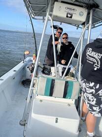 Two anglers proudly displaying a caught fish aboard a fishing boat, enjoying a day on the water.