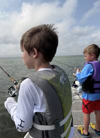 Two young anglers focused on fishing from a boat, showcasing the excitement of a day on the water.