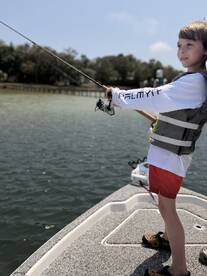 A young angler casting from a boat in calm waters, showcasing the excitement of fishing in a family-friendly environment.