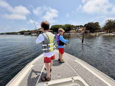 Two young anglers fishing from a boat in a calm waterway, showcasing a fun family fishing experience.