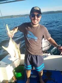 A proud angler holding a large fish while on a boat, showcasing a successful fishing trip.