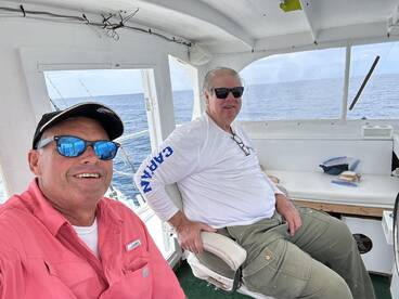 Two anglers relaxing inside the boat's helm area, enjoying a day on the open water.