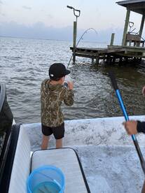 A young angler is reeling in a catch from the boat, showcasing the excitement of fishing in a coastal environment.