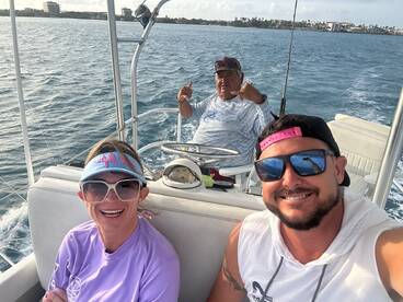 Two anglers enjoying a day on the water, seated in the boat's interior with a scenic backdrop of the coastline.