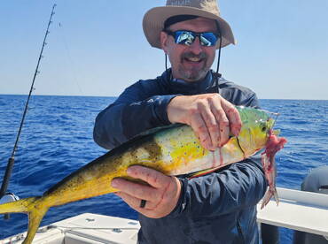 Angler proudly displaying a vibrant Mahi Mahi while fishing offshore, showcasing the excitement of a successful catch.