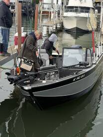 Two anglers preparing on a sleek fishing boat at the dock, showcasing a well-equipped setup for a day on the water.