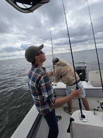 Two anglers actively fishing on a boat, with rods in hand, enjoying a cloudy day on the water.