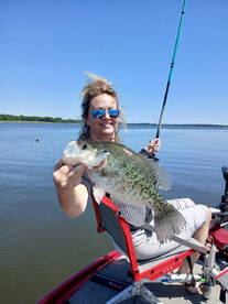 Angler proudly displaying a large Crappie while fishing from a boat on a sunny day.