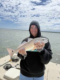 Angler proudly displaying a Redfish while fishing on a sunny day at the dock.