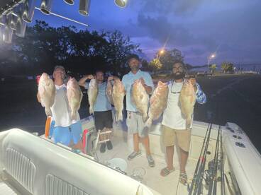 A group of anglers proudly displaying their catch of large Snapper on a fishing charter, showcasing a successful day on the water.