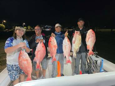 Group of anglers proudly displaying their catch of Red Snapper after a night fishing trip.