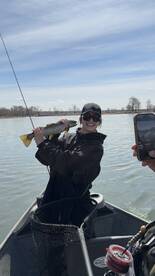 Angler proudly displaying a large trout while fishing on a river, capturing a joyful moment with friends.
