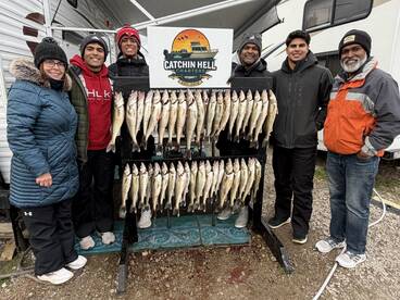 A group of anglers proudly displaying their catch of Walleye on a catch board after a successful fishing trip with Catchin Hell Charters.