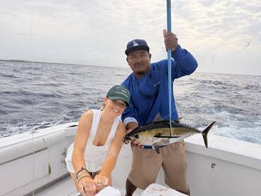 A proud angler holding a large Yellowfin Tuna while fishing on a charter boat, showcasing a successful day on the water.