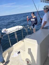 A young angler proudly displaying a freshly caught fish while fishing on a boat in open water.