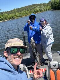 A group of anglers proudly displaying their catch of multiple fish while enjoying a sunny day on the water.