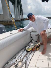 Angler posing with a variety of fish including Barracuda and Mahi-Mahi aboard a boat, showcasing a successful day of fishing.