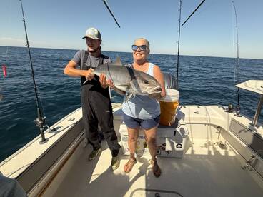 A proud moment on the boat as a woman holds a large Amberjack, showcasing a successful fishing trip.