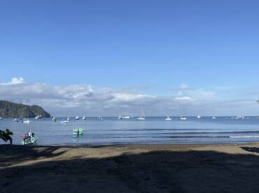 A scenic view of multiple fishing boats anchored in a calm bay, with a beach area in the foreground, perfect for a day of fishing adventures.