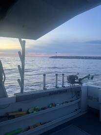 Interior view of a KingFisher boat showcasing the console and fishing gear, with a serene sunset over the water.