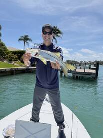 Angler proudly displaying a Snook caught while fishing from a boat in a scenic coastal environment.