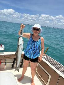 A smiling angler proudly displaying a large fish while fishing on a sunny day in coastal waters.