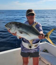 Angler proudly displaying a large Jack Crevalle while fishing offshore, showcasing a successful day on the water.