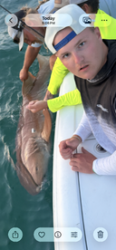 A young angler looks surprised while helping to reel in a large shark during a fishing trip.