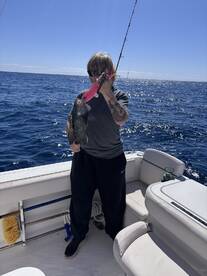 Angler holding a freshly caught Snapper while fishing on a boat in open waters.